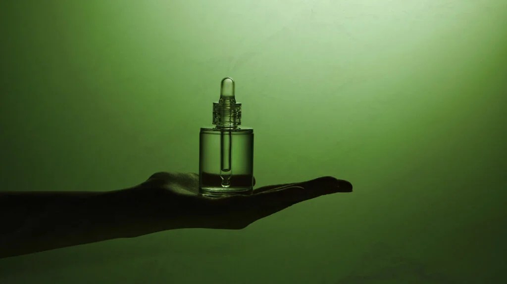 green tint photo of aromatherapy oil vial on an outstretched hand
