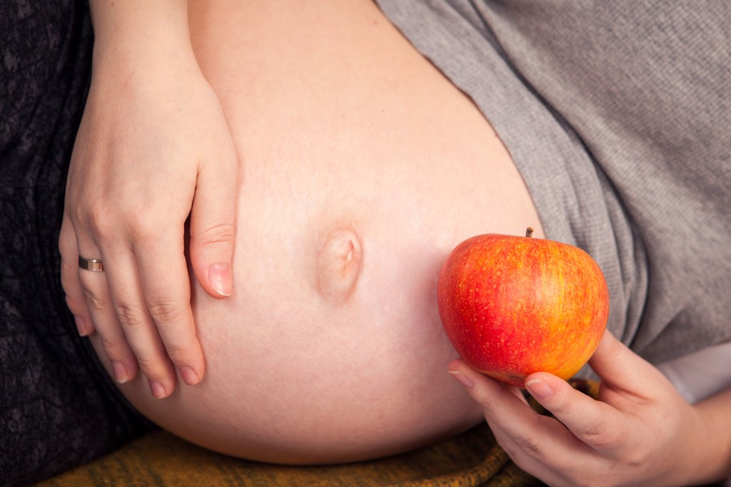 Pregnant woman holding apple.