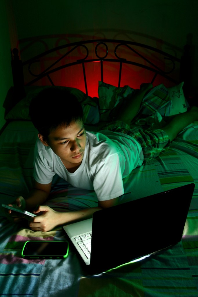 teenager in bed staring at computer